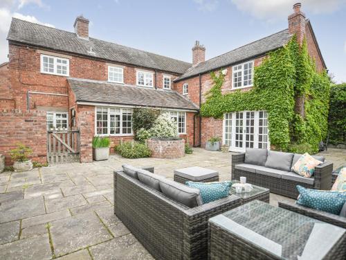an outdoor patio with wicker furniture in front of a brick building at Home Farm House in Dorrington