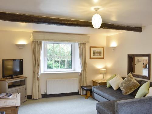 a living room with a couch and a window at Drumlins Cottage in Gatebeck