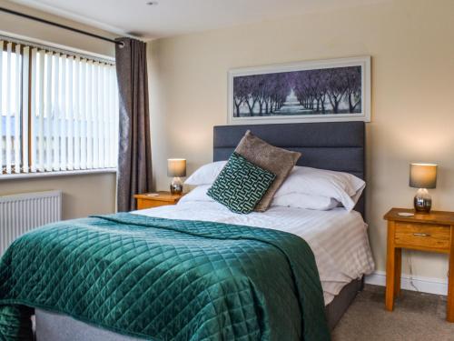 a bedroom with a bed with a green blanket at Swan House in Carnforth
