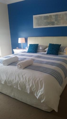 a large white bed with blue pillows on it at Residence On Robe in Robe