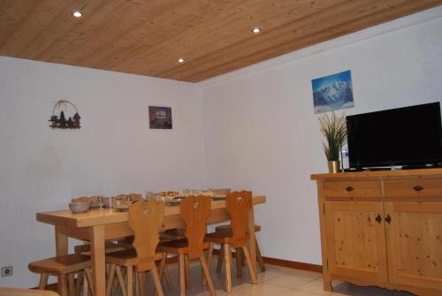 comedor con mesa con sillas y TV de pantalla plana en Vieille Bergerie 2, en Le Fernuy