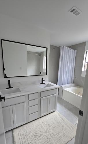 a white bathroom with two sinks and a large mirror at Weslynn's Minimalistic Stay in Humble