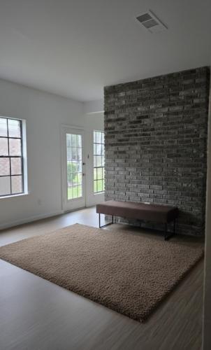 a living room with a bench against a brick wall at Weslynn's Minimalistic Stay in Humble
