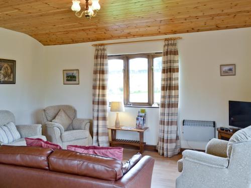 a living room with a leather couch and chairs at Woodside Lodge - Hw7520 in Penybont