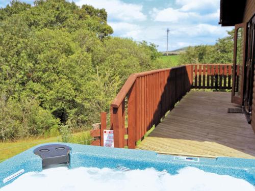 a hot tub on a house with a wooden deck at Woodside Lodge - Hw7520 in Penybont