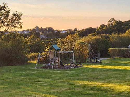 a park with a playground and a swing set at Primrose Lodge in Holsworthy