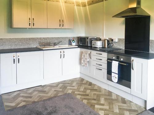 a kitchen with white cabinets and a black counter top at Little Folly in  Liscombe