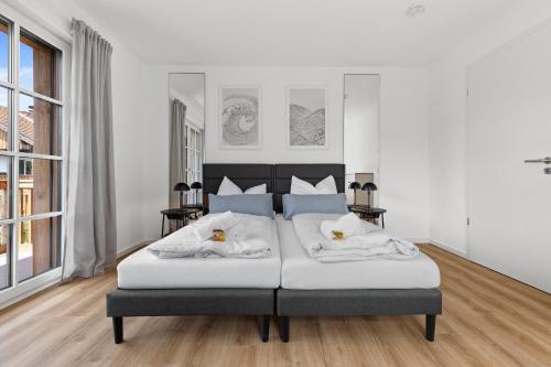 une chambre avec un grand lit blanc avec deux oreillers dans l'établissement BALANCED Münsing Apartments, vollausgestatte Ferienwohnungen Nähe Starnberger See, à Münsing