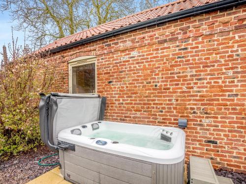 una vasca da bagno situata accanto a un edificio in mattoni di The Old Granary a Cumberworth