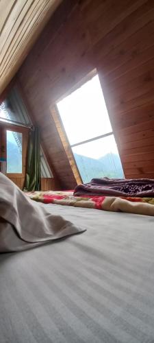two beds in a room with a window at Skytouch cottage Lambri pass view in Jibhi