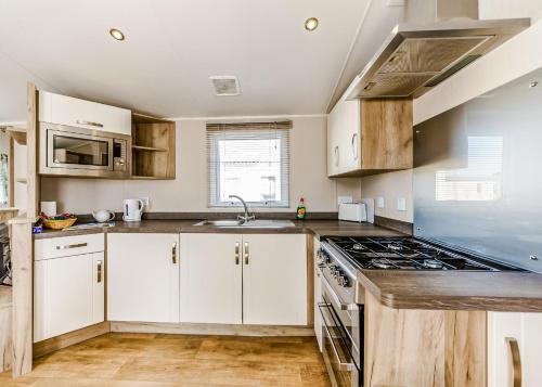 a kitchen with white cabinets and a stove top oven at Riverside Holiday Village in Uphill