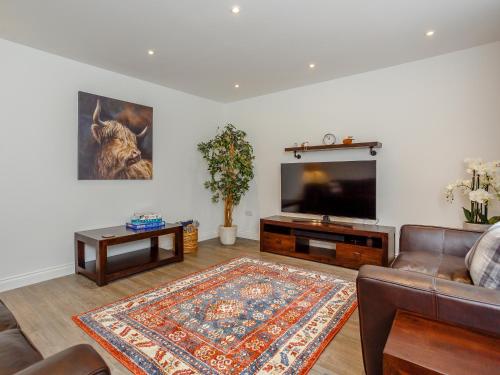 Una sala de estar con un sofá y un televisor de pantalla plana. en Strathclaggan, en Aberlour