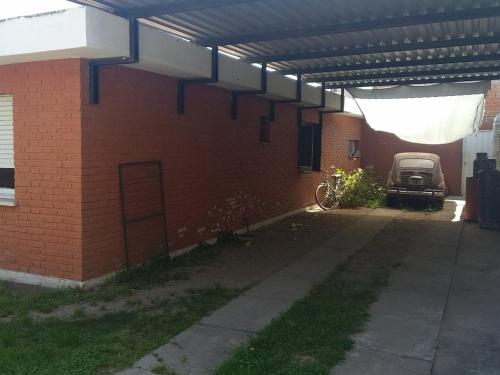 ein Backsteingebäude mit einem unter einem Dach geparkten Auto in der Unterkunft Casa Milu in Mina Clavero