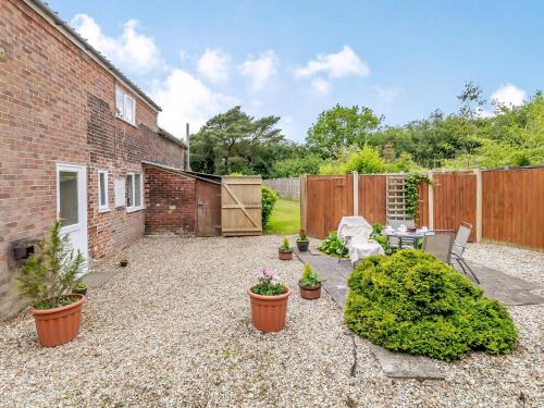 a backyard with plants and a brick building at Sunnyside in Colkirk