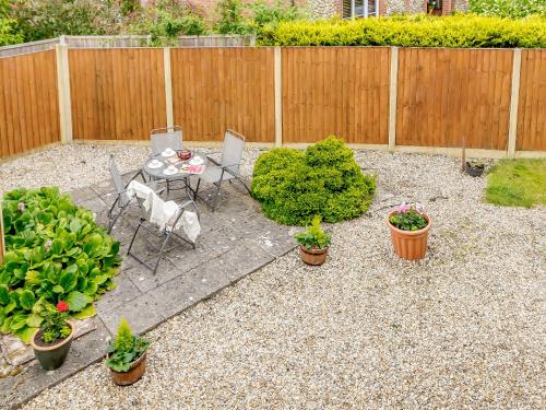a patio with a table and chairs and potted plants at Sunnyside in Colkirk