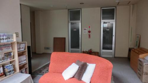 a living room with an orange chair with two pillows at Oomukou Ryokan in Hakuba