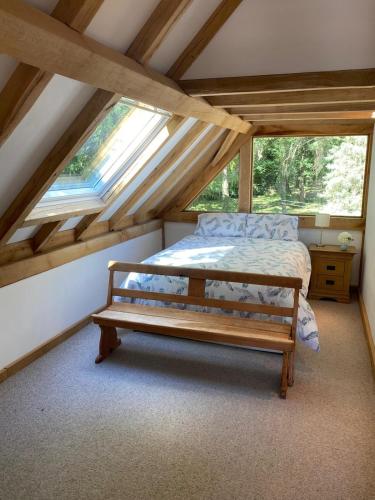 a bedroom with a bed and a bench in a attic at Spirit Lake in Dorking