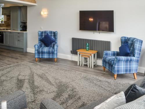 ein Wohnzimmer mit 2 blauen Stühlen und einem Tisch in der Unterkunft Mollies View in Wooler