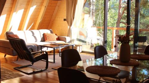 a living room with a couch and chairs and a glass table at Molika Forest House in Kolašin
