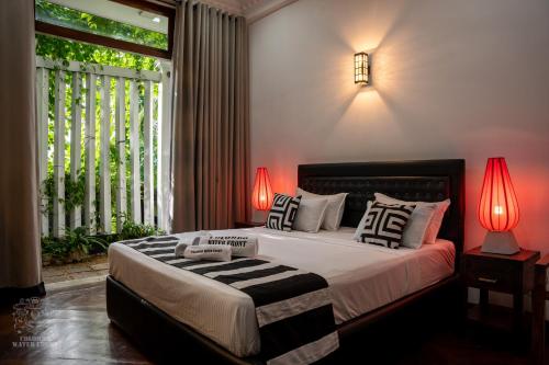 a bedroom with a bed with two lamps and a window at COLOMBO Water Front in Boralesgamuwa