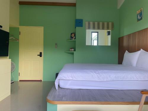 a bedroom with a white bed and a green wall at Blue Sea and Sunny B&B in Toucheng