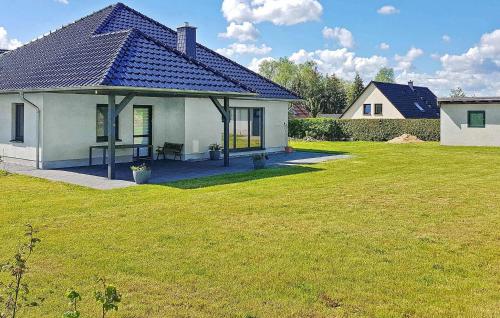 a white house with a blue roof on a yard at Ferienhaus Grünow Ot Ollendorf in Blankensee
