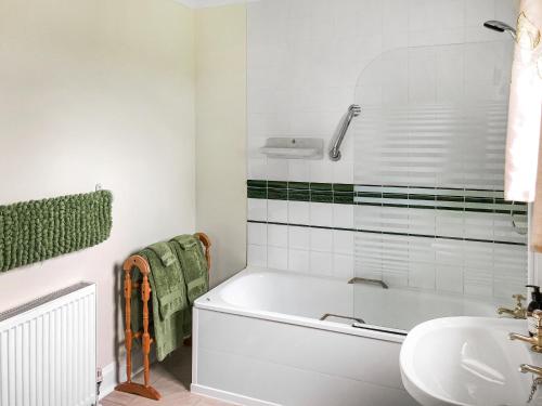 a white bathroom with a tub and a sink at Capelrig in Balfron