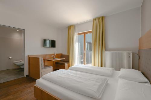 a bedroom with two beds and a desk and a sink at Hotel Post Gries in Bolzano