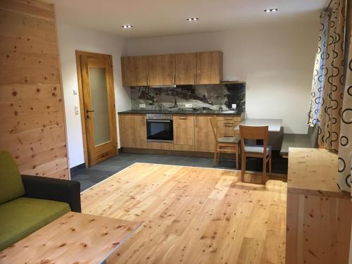 a living room with a kitchen with wooden floors at Refugium Dolomiten & Chalet in Sillian