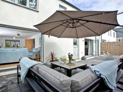 a patio with a couch and a table with an umbrella at Oakwood in Saint Endellion