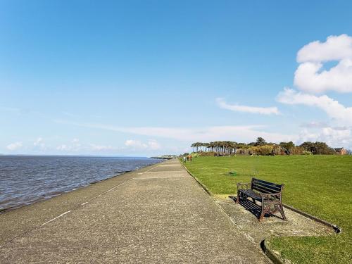 a bench sitting on the side of a sidewalk near the water at The Police Station - Uk45642 in Silloth