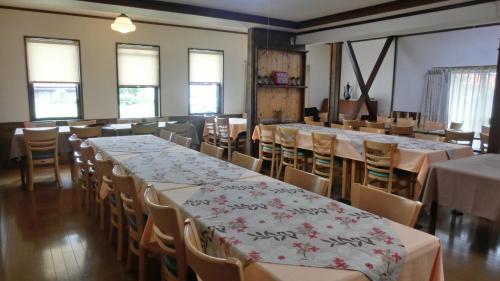 a dining room with tables and chairs and windows at Oomukou Ryokan in Hakuba