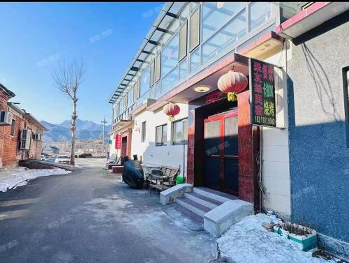 a building with a front door with snow on the ground at Jinshanling Great Wall聚友缘民宿 in Gubeikou