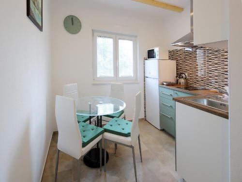 een kleine keuken met een glazen tafel en witte stoelen bij Apartment in Šilo with Sea View Balcony in Šilo