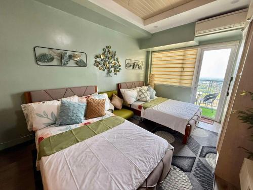 a bedroom with two beds and a couch and a window at Vacay shine tagaytay staycation in Kaybagal