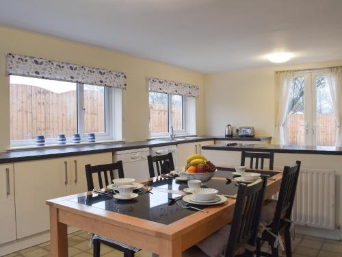 a kitchen with a wooden table and chairs in a kitchen at Brookside Cottage in Forton