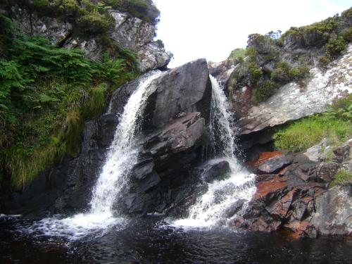 a waterfall on the side of a rocky cliff at Sandwick Bay Guest House in Stornoway