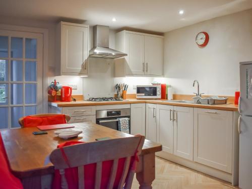 a kitchen with white cabinets and a wooden table at Felbridge Cottage in Bardon Mill
