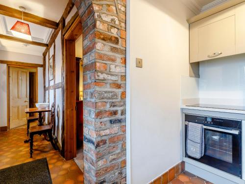 a kitchen with a brick wall and a stove at The Pigsty - Uk30945 in Barthomley