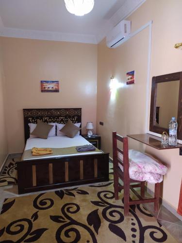a bedroom with a bed and a mirror and a chair at Desert Dream Apartment in Merzouga