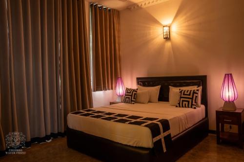 a bedroom with a bed with two lamps on it at COLOMBO Water Front in Boralesgamuwa