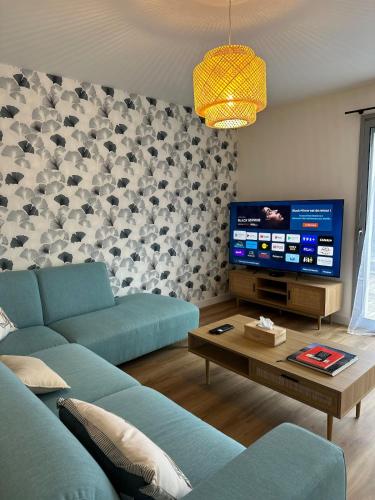 ein Wohnzimmer mit einem blauen Sofa und einem Fernseher in der Unterkunft Le Nid Des Grèves avec jacuzzi in Langueux