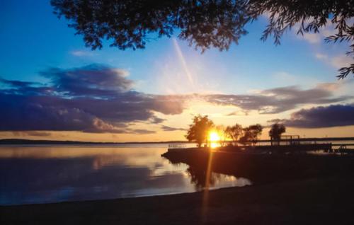 a sunset over a body of water with the sun setting at Ferienhaus Verchen in Verchen
