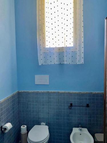 a blue bathroom with a toilet and a sink at Bnb I Gelsomini Selinunte in Marinella di Selinunte