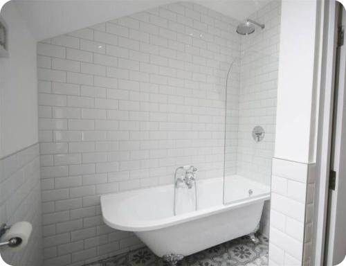 a white bathroom with a tub and a toilet paper roll at Cardiff central in Cardiff