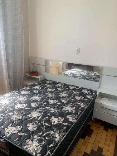 a bedroom with a bed with a black and white comforter at Quarto em casa arborizada in Belém