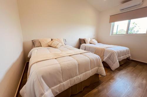 two beds in a small bedroom with a window at Villa Blanca in Esterillos Este