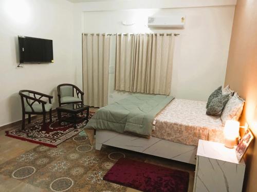 a bedroom with a bed and a chair and a television at Krishna's Paradise in Rishīkesh