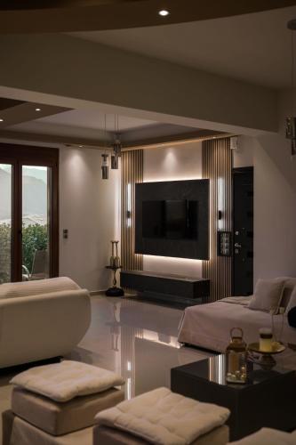 a large living room with a couch and a tv at Villa Under Meteora in Kalabaka