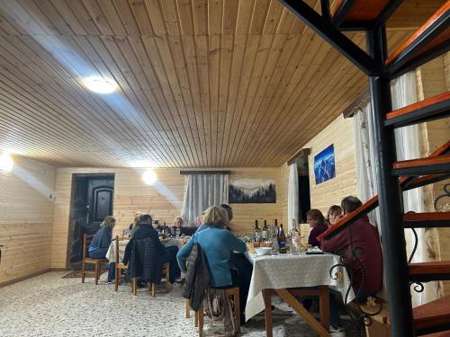 a group of people sitting at tables in a restaurant at Bata GuesThouse in Adishi